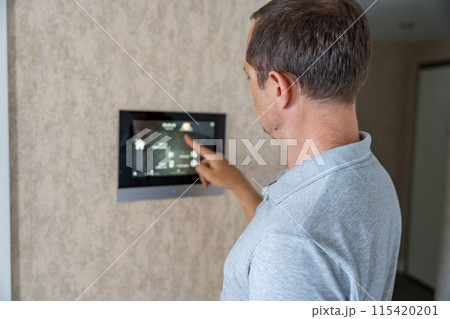 Man using tablet panel application for control smart home living. Wireless device controller for home automation IoT on the wall Man using tablet panel application for control smart home living. Wireless device controller for home automation IoT on the wall 115420201