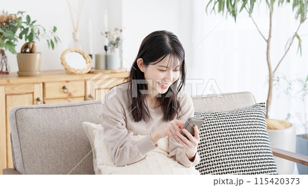 リビングでスマホを見る女性 115420373