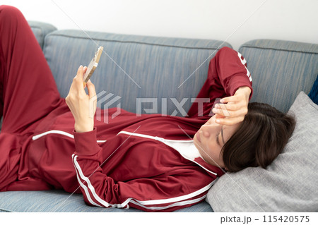 ソファーでスマホを見る女性 ストレス ソファーでスマホを見る女性 ストレス 115420575