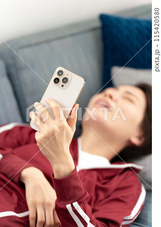 ソファーでスマホを見る女性　ストレス 115420580