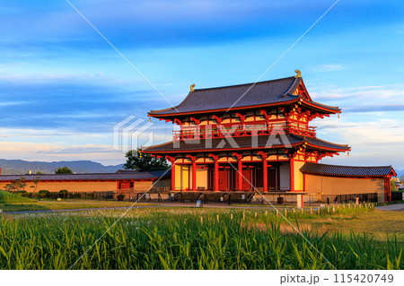 奈良平城京跡朱雀門ひろばの夕景　夕日に照らされ黄金色に輝く朱雀門① 115420749