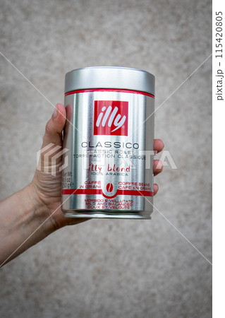 Illy coffee metal can packaging in hand on a light background. Logo and branding 115420805