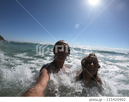 Sea waves splashing on happy couple. 115420902