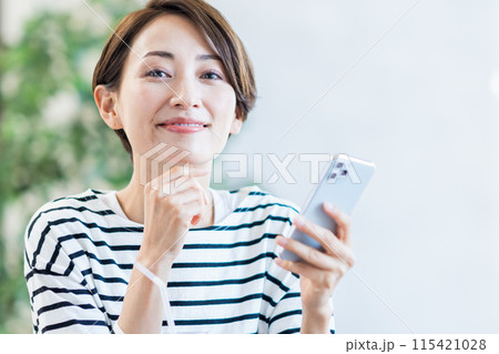 カフェでスマホを操作するミドル女性。 カフェでスマホを操作するミドル女性。 115421028