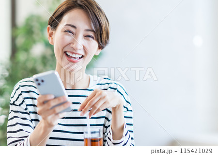 カフェでスマホを操作するミドル女性。 カフェでスマホを操作するミドル女性。 115421029