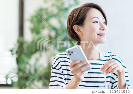 カフェでスマホを操作するミドル女性。 カフェでスマホを操作するミドル女性。 115421030
