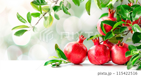 Close-up of ripe Pomegranates on a tree branch. Vibrant fruits and green leaves convey freshness and healthy living 115422516
