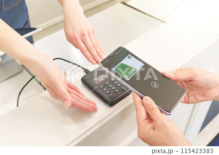 キャッシュレス決済を行うお客と店員の手元 115423383