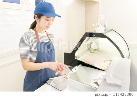タブレットレジを使うエプロン姿の女性店員 タブレットレジを使うエプロン姿の女性店員 115423390