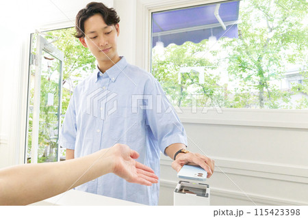 スマホをかざしてキャッシュレス決済をする若い男性客 115423398