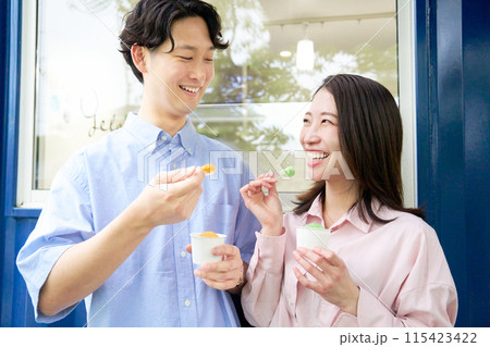 笑顔でジェラートを食べる若い男女 笑顔でジェラートを食べる若い男女 115423422