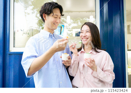 笑顔でジェラートを食べる若い男女 115423424