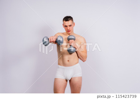 Shirtless bodybuilder holding dumbell and showing his muscular arms. Shirtless bodybuilder holding dumbell and showing his muscular arms. 115423739