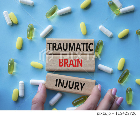 Traumatic Brain Injury symbol. Concept words Traumatic Brain Injury on wooden blocks. Beautiful blue background with pills. Doctor hand. Healthcare and Traumatic Brain Injury concept. Copy space. Traumatic Brain Injury symbol. Concept words Traumatic Brain Injury on wooden blocks. Beautiful blue background with pills. Doctor hand. Healthcare and Traumatic Brain Injury concept. Copy space. 115425726