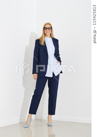 Cute woman dressed in a chic navy blue suit with matching trousers and light blue heels Cute woman dressed in a chic navy blue suit with matching trousers and light blue heels 115425813