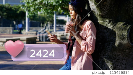 Side view of a female Caucasian teenager wearing a cap leaning against a tree in the park 115426854
