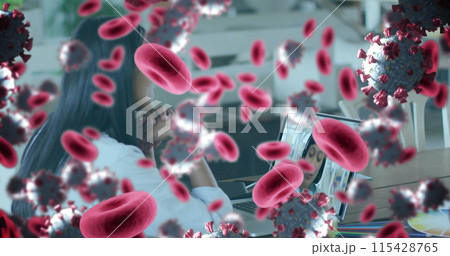 Image of covid 19 cells and red blood cells over businesswoman using laptop 115428765