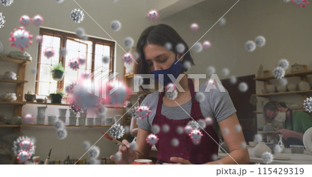 Image of virus cells over caucasian woman with face mask forming pottery 115429319