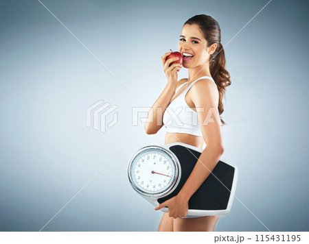 Eating apple, portrait or woman with scale for healthy diet in studio for fitness workout, exercise or training. Lose weight, mockup space or girl with fruit for vitamin c or detox on blue background 115431195