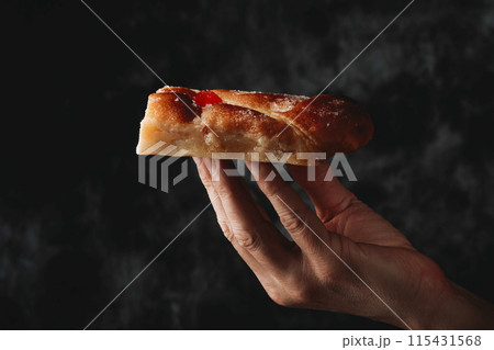 piece of catalan coca de sant joan in his hand 115431568
