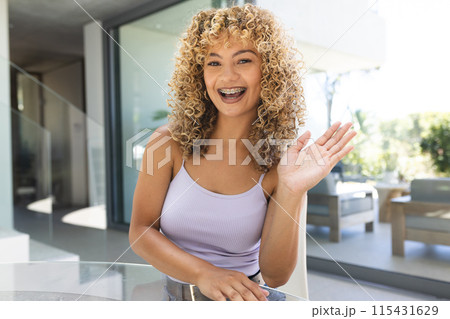 Young biracial woman greets warmly from her modern home on a video call 115431629