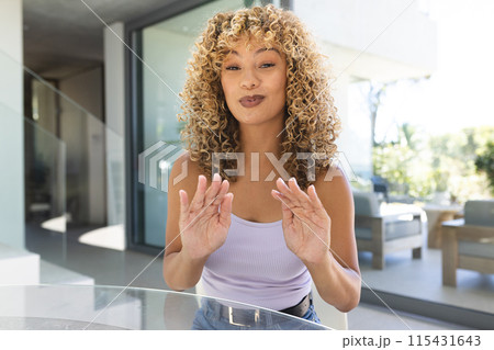 Young biracial woman blowing a kiss at home on a video call 115431643