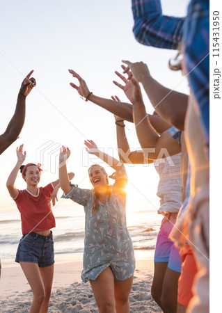 Diverse young friends enjoy a beach party at sunset, with copy space 115431950