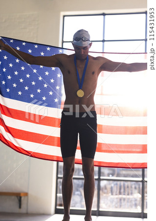 Proud young biracial male athlete swimmer displays a gold medal, with copy space 115431953