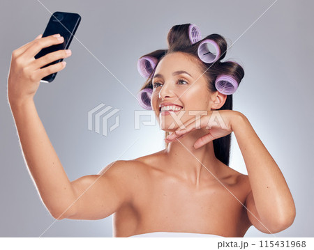 Hair roller, woman and phone for selfie with transformation results, social media and blog app in studio. Mobile picture, haircare influencer and salon tools for curling hairstyle by grey background Hair roller, woman and phone for selfie with transformation results, social media and blog app in studio. Mobile picture, haircare influencer and salon tools for curling hairstyle by grey background 115431968