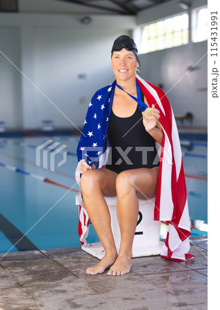 Caucasian woman draped in an American flag at a poolside, with medal, with copy space Caucasian woman draped in an American flag at a poolside, with medal, with copy space 115431991