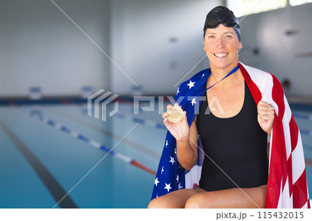 Caucasian woman showcases her gold medal poolside with an American flag Caucasian woman showcases her gold medal poolside with an American flag 115432015