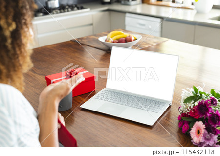 Biracial woman enjoys a surprise gift at home during an online date video call, with copy space 115432118