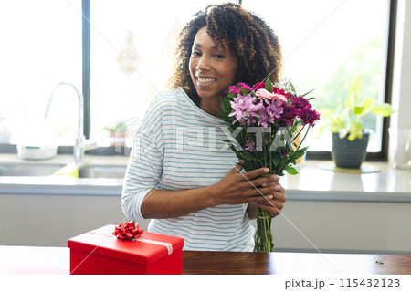 Biracial woman holding flowers at home during an online date video call Biracial woman holding flowers at home during an online date video call 115432123