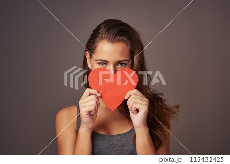 Portrait, love and woman with paper heart in studio for romance, support or donate isolated on background. Face, care or model with sign for valentines day, kindness or hide on emoji for social media Portrait, love and woman with paper heart in studio for romance, support or donate isolated on background. Face, care or model with sign for valentines day, kindness or hide on emoji for social media 115432425