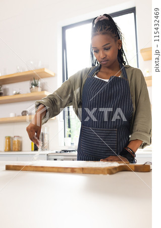 A young African American woman is cooking in a bright kitchen A young African American woman is cooking in a bright kitchen 115432469