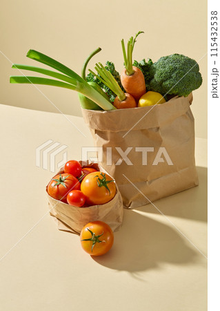 Photo of view from above on a yellow countertop contains two paper bag placed by side, both containing fresh vegetable ingredient. Advertising photo for culinary, dietary or vegetarian 115432538