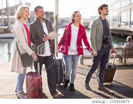 Tourists with suitcases and camera walk along the pavement in port of European city 115432675