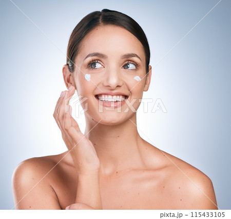 Lotion, woman and smile in studio for skincare, cream and moisturizer on blue background. Dermatology, product and girl with happiness for results, routine and cosmetics or sunscreen for protection 115433105