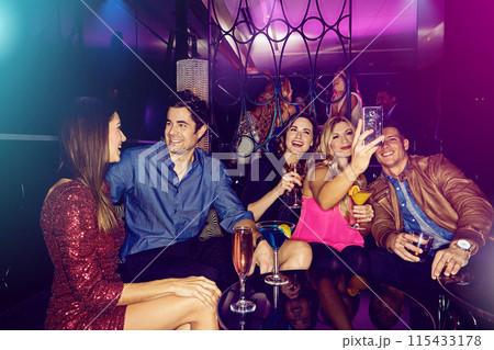 People, selfie or friends in nightclub with smile, drinks or cocktails for memory, vip event or reunion. Pictures, men or happy women on dark party couch for alcohol, photograph or social celebration 115433178