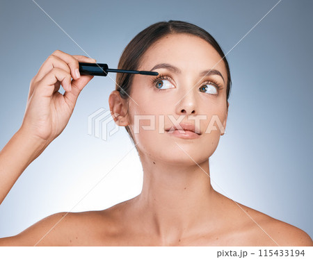 Woman, mascara and studio with hand for makeup, cosmetic and application on blue background. Beauty, selfcare and product for female person, beautician and glamour for confidence and eyelashes 115433194