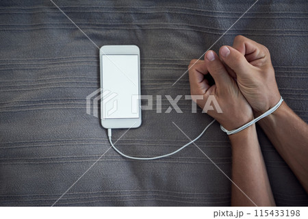 Phone screen, hands tied or internet addiction with cable handcuff on bed with above mockup for control in a house. Space, app or wrist with smartphone for network, social media and web manipulation Phone screen, hands tied or internet addiction with cable handcuff on bed with above mockup for control in a house. Space, app or wrist with smartphone for network, social media and web manipulation 115433198