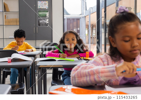 African American boy and two biracial girls focused on their schoolwork in a school classroom African American boy and two biracial girls focused on their schoolwork in a school classroom 115433265