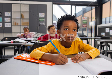 African American boy focused on his schoolwork in a school classroom setting African American boy focused on his schoolwork in a school classroom setting 115433280