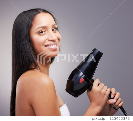 Cosmetics, woman and happy portrait with hairdryer in studio grey background for wellness and self care. Female person, heat treatment and smile with equipment isolated on backdrop for salon shine 115433376