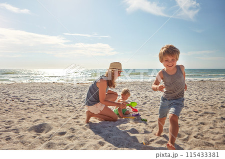 Happy, mother and children playing on the beach on family vacation, holiday or adventure in summer. Boy, woman and kids with outdoor ocean for fun energy and happiness with game while running 115433381