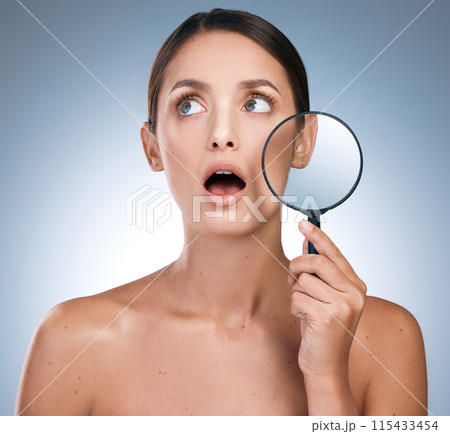Woman, shock and magnify glass for skincare or beauty, botox and anti aging on blue background. Cosmetology, retinol and spot control for treatment, pamper and dermatology for female person in studio 115433454
