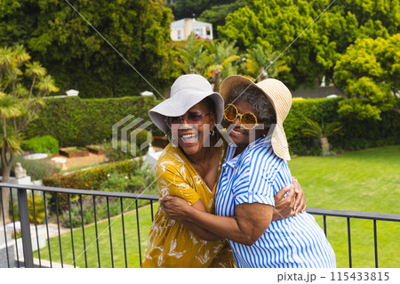 Senior African American woman and senior biracial woman share a joyful embrace outdoors on vacation 115433815