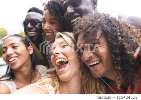 Diverse group of friends share a joyful moment, laughing together outdoors 115434618