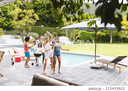 Diverse group of friends enjoying a barbecue by the poolside with copy space 115435022