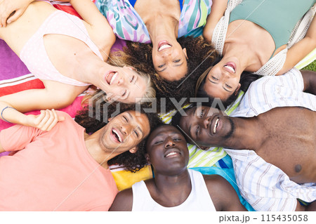 Diverse group of friends lying down close together, smiling at the camera Diverse group of friends lying down close together, smiling at the camera 115435058